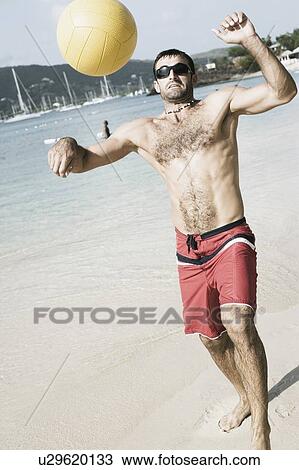 Mid adult man playing beach volleyball on the beach View Large Photo Image Stock Image - Mid adult man playing beach volleyball on the beach. Fotosearch