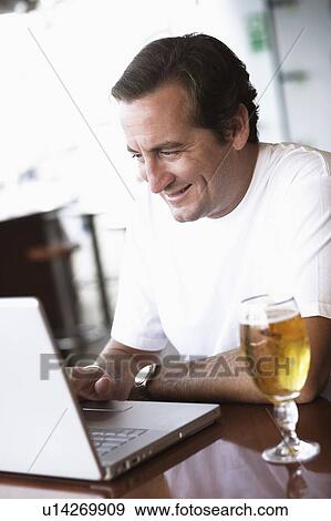 Mid adult man using a laptop and smiling View Large Photo Image Stock Photo - Mid adult man using a laptop and smiling. Fotosearch