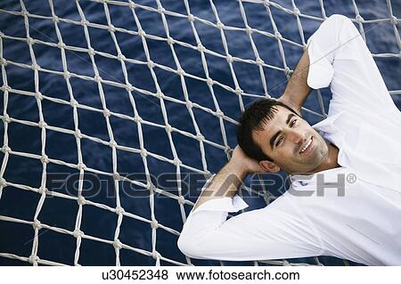 Portrait of a mid adult man lying on a net and smiling View Large Photo Image Stock Photo - Portrait of a mid adult man lying on a net and smiling. Fotosearch