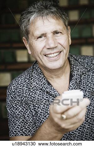 Stock Image - Portrait of a senior man holding a mobile phone and smiling. Fotosearch