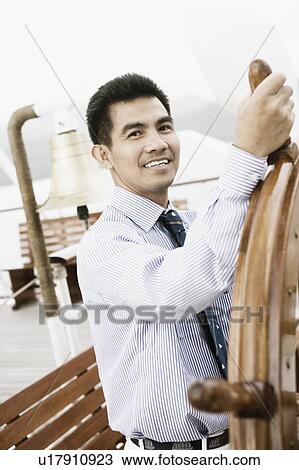 Young man holding the helm of a sailing ship and smiling View Large Photo Image Stock Image - Young man holding the helm of a sailing ship and smiling. Fotosearch