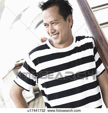 Young man leaning against a banister and smiling View Large Photo Image Stock Image - Young man leaning against a banister and smiling. Fotosearch