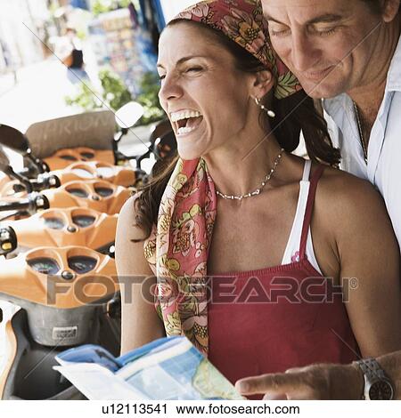 Close-up of a mid adult couple holding a catalog and smiling View Large Photo Image Stock Image - Close-up of a mid adult couple holding a catalog and smiling. Fotosearch