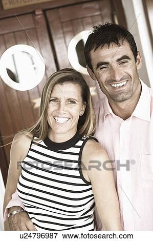 Close-up of a mid adult man with his arm around a mid adult woman and smiling View Large Photo Image Stock Photo - Close-up of a mid adult man with his arm around a mid adult woman and smiling. Fotosearch