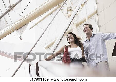 Stock Photo - Low angle view of a mid adult couple standing with their arms outstretched. Fotosearch
