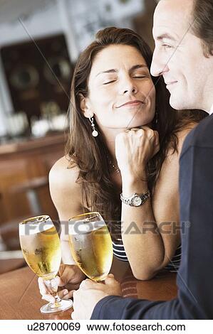 Mid adult couple sitting in a bar and holding beer in stem glasses View Large Photo Image Stock Photo - Mid adult couple sitting in a bar and holding beer in stem glasses. Fotosearch