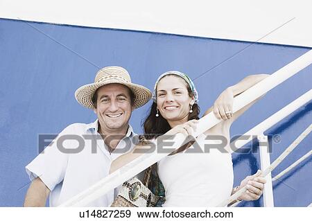 Portrait of a mid adult couple standing on the staircase of a cruise ship and smiling View Large Photo Image Stock Photo - Portrait of a mid adult couple standing on the staircase of a cruise ship and smiling. Fotosearch