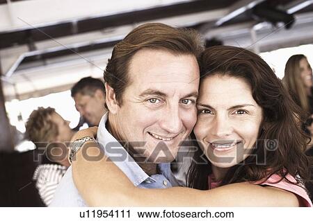 Stock Image - Portrait of a mid adult couple embracing each other in a nightclub. Fotosearch