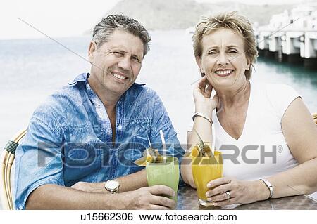 Portrait of a senior man and a mature woman holding glasses of juice and smiling View Large Photo Image Stock Photograph - Portrait of a senior man and a mature woman holding glasses of juice and smiling. Fotosearch