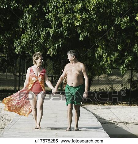 Senior man and a mature woman holding each other's hands and walking on a jetty View Large Photo Image Stock Photography - Senior man and a mature woman holding each other's hands and walking on a jetty. Fotosearch