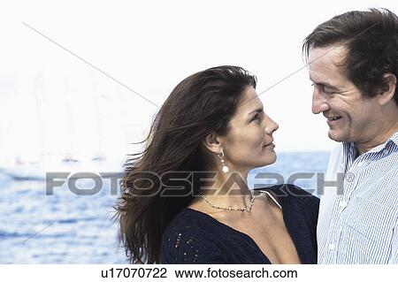 Stock Image - Side profile of a mid adult couple looking at each other. Fotosearch