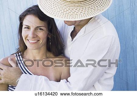 Stock Image - Side profile of a mid adult man embracing a mid adult woman. Fotosearch