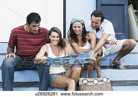 Two mid adult couples sitting on steps and looking at a brochure View Large Photo Image Stock Image - Two mid adult couples sitting on steps and looking at a brochure. Fotosearch