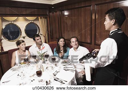 Waiter serving wine bottle to two mid adult couples View Large Photo Image Stock Photograph - Waiter serving wine bottle to two mid adult couples. Fotosearch