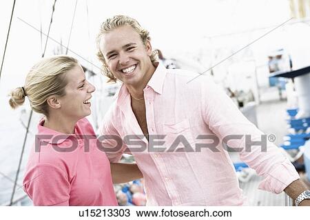 Young couple standing with their arms around each other and smiling View Large Photo Image Stock Image - Young couple standing with their arms around each other and smiling. Fotosearch