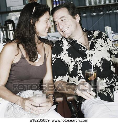 Stock Photo - Close-up of a mid adult couple holding glasses of drink in a restaurant. Fotosearch