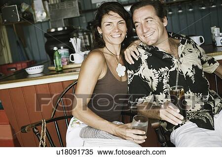 Close-up of a mid adult couple holding glasses of drink in a restaurant View Large Photo Image Stock Photography - Close-up of a mid adult couple holding glasses of drink in a restaurant. Fotosearch