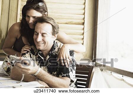Stock Image - Close-up of a mid adult couple looking at a digital camera. Fotosearch
