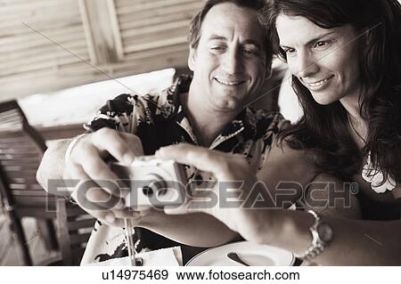 Close-up of a mid adult couple operating a digital camera in a restaurant View Large Photo Image Stock Photo - Close-up of a mid adult couple operating a digital camera in a restaurant. Fotosearch