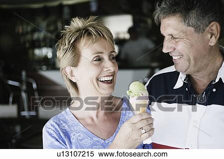 Mature woman holding an ice-cream cone with a senior man smiling beside her View Large Photo Image Stock Photography - Mature woman holding an ice-cream cone with a senior man smiling beside her. Fotosearch