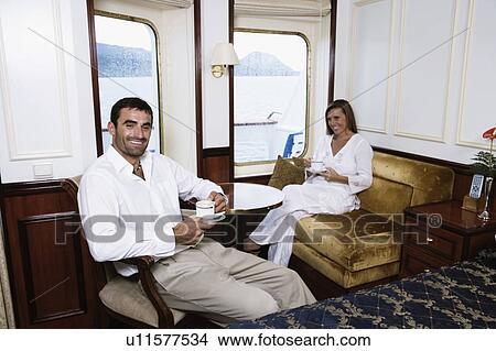 Mid adult couple drinking tea in a cabin of a sailing ship and smiling View Large Photo Image Picture - Mid adult couple drinking tea in a cabin of a sailing ship and smiling. Fotosearch