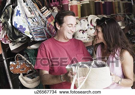Mid adult couple holding a hand bag and smiling View Large Photo Image Picture - Mid adult couple holding a hand bag and smiling. Fotosearch