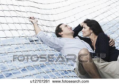 Stock Image - Mid adult couple lying in a hammock. Fotosearch