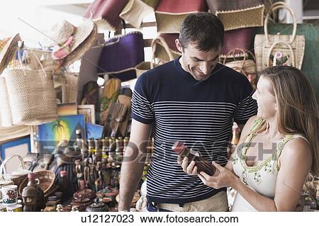 Stock Image - Mid adult woman holding a bottle of sauce with a mid adult man smiling. Fotosearch