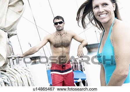 Stock Photo - Mid adult woman smiling with a mid adult man standing behind her. Fotosearch
