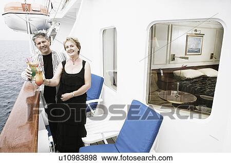 Stock Photo - Portrait of a mature woman and a senior man holding glasses of cocktail and smiling. Fotosearch