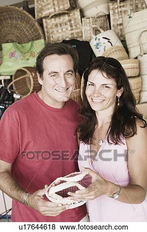 Stock Photo - Portrait of a mid adult couple holding a hand bag and smiling. Fotosearch