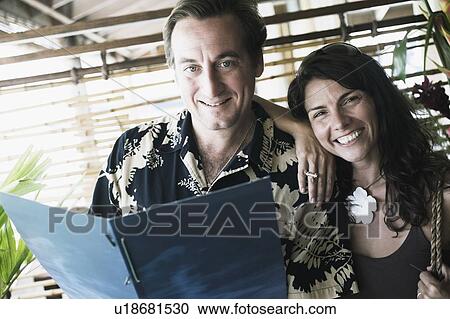 Stock Image - Portrait of a mid adult man holding a menu card with a mid adult woman beside him. Fotosearch