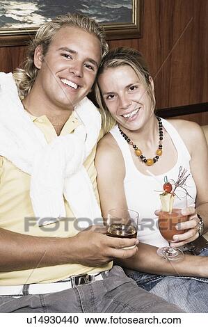 Stock Image - Portrait of a young couple holding glasses of cocktail. Fotosearch