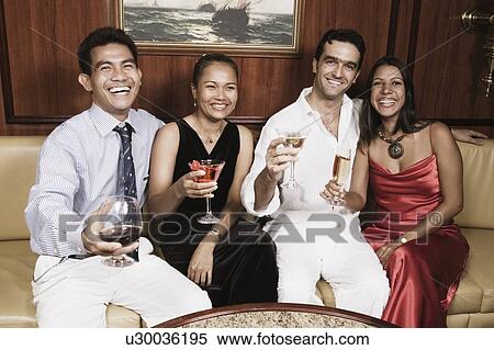 Portrait of two young couples sitting on a couch with holding their glasses and smiling View Large Photo Image Stock Photography - Portrait of two young couples sitting on a couch with holding their glasses and smiling. Fotosearch