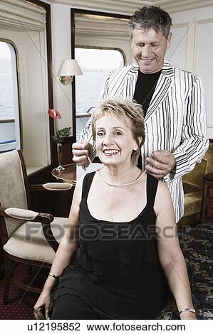 Stock Image - Senior man giving a necklace to a mature woman and smiling. Fotosearch