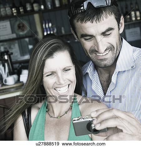 Young man and a mid adult woman looking at a digital camera View Large Photo Image Stock Photo - Young man and a mid adult woman looking at a digital camera. Fotosearch