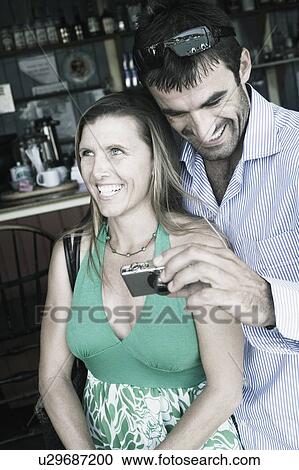 Young man standing with a mid adult woman and holding a digital camera View Large Photo Image Stock Image - Young man standing with a mid adult woman and holding a digital camera. Fotosearch