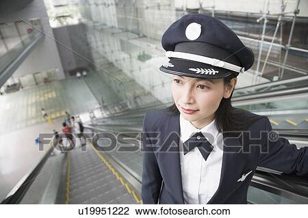 Stock Image - Close-up of a female pilot standing on an escalator. Fotosearch