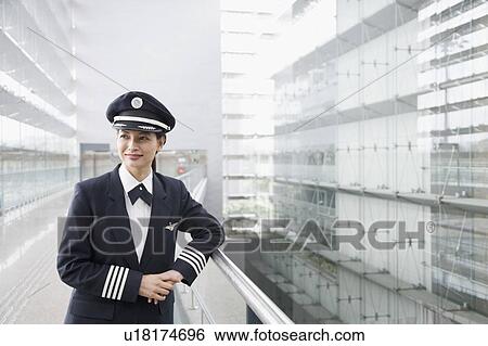 Stock Photograph - Female pilot leaning against a railing. Fotosearch