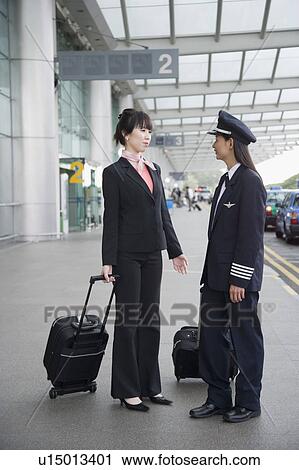 Stock Image - Female pilot talking to a female cabin crew. Fotosearch