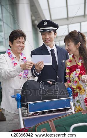 Stock Image - Mature couple showing their airplane tickets to a pilot. Fotosearch