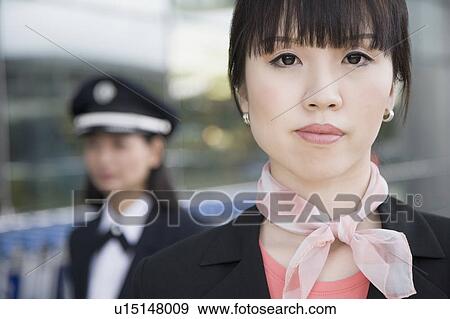 Stock Photo - Portrait of a female cabin crew with a female pilot behind her. Fotosearch