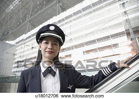 Portrait of a female pilot standing on an escalator View Large Photo Image Stock Photograph - Portrait of a female pilot standing on an escalator. Fotosearch