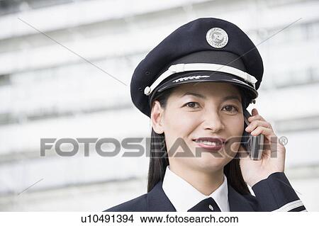 Picture - Portrait of a female pilot talking on a mobile phone and smiling. Fotosearch