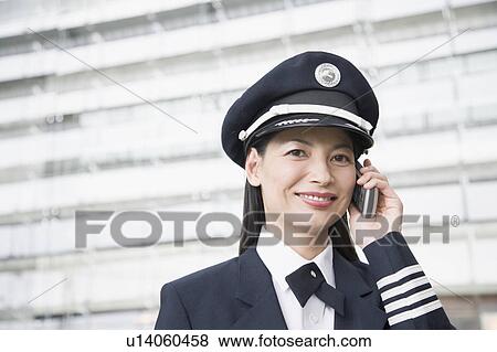 Stock Photo - Portrait of a female pilot talking on a mobile phone and smiling. Fotosearch