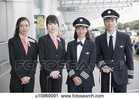Stock Image - Portrait of a male and a female pilot standing with two cabin crew members. Fotosearch