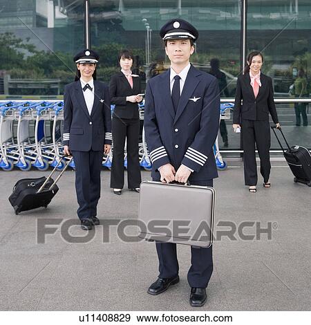 Portrait of a pilot holding a briefcase with a female pilot and two cabin crews standing in the background View Large Photo Image Stock Photo - Portrait of a pilot holding a briefcase with a female pilot and two cabin crews standing in the background. Fotosearch