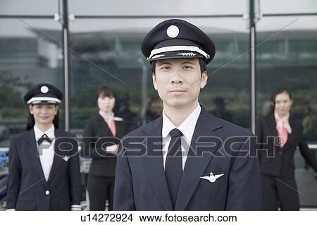 Picture - Portrait of a pilot with a female pilot and two cabin crews standing in the background. Fotosearch