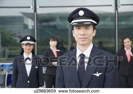Portrait of a pilot with a female pilot and two cabin crews standing in the background View Large Photo Image Stock Photo - Portrait of a pilot with a female pilot and two cabin crews standing in the background. Fotosearch