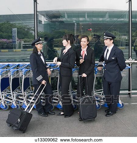 Two female cabin crews standing with two pilots at an airport View Large Photo Image Stock Image - Two female cabin crews standing with two pilots at an airport. Fotosearch